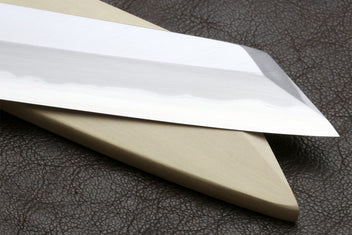 Japanese chef knife blade and handle shown in profile on dark leather