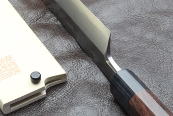 Japanese chef knife tang and blade base close-up with dark handle on leather