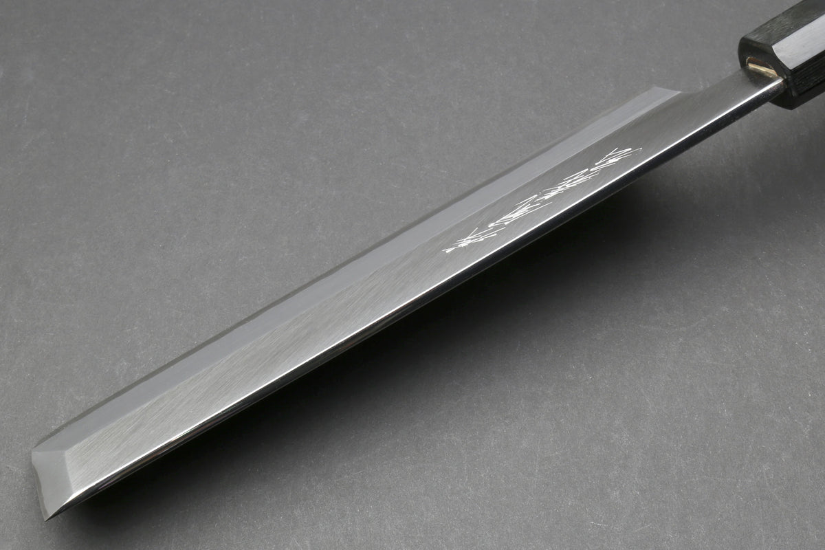 Japanese chef knife blade close-up with polished edge and dark bolster