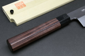 Japanese chef knife wooden handle close-up with dark bolster and pale saya