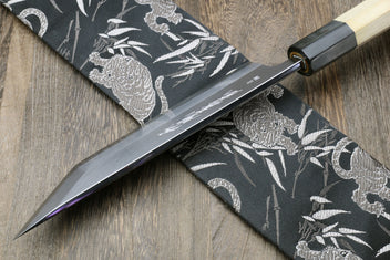 Eel filet knife with pointed blade crossing on dark patterned fabric