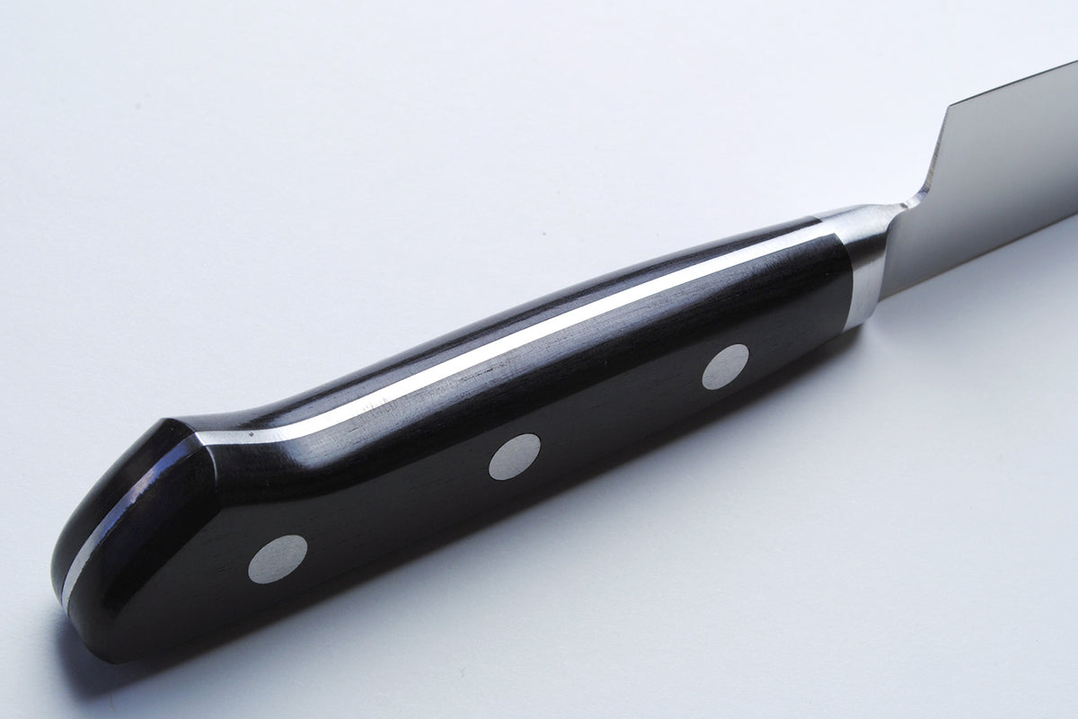 Santoku chef’s knife handle close-up with black scales and silver rivets on dark bolster