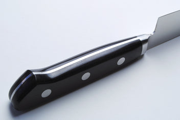 Santoku chef’s knife handle close-up with black scales and silver rivets on dark bolster
