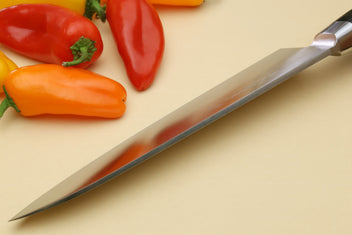 Double-edged deba fillet knife with pointed silver blade and dark handle, side view