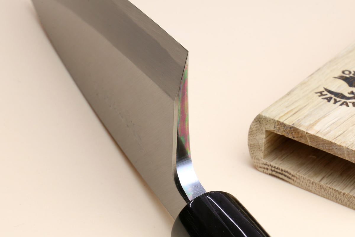 Deba knife close-up: white blade edge, black ferrule, light magnolia handle