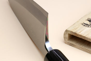 Deba knife close-up: white blade edge, black ferrule, light magnolia handle