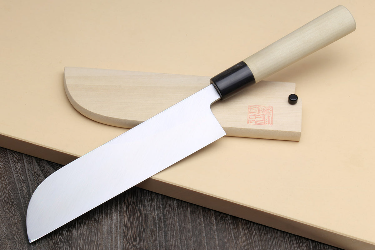 Japanese vegetable chef knife with dark blade and light wood handle, shown on wooden board.