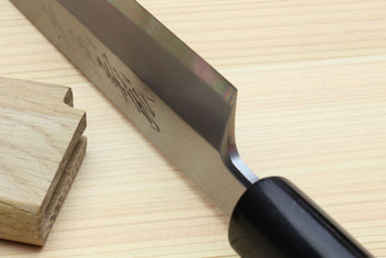 Yanagi knife partly in saya, showing blade edge and rosewood handle