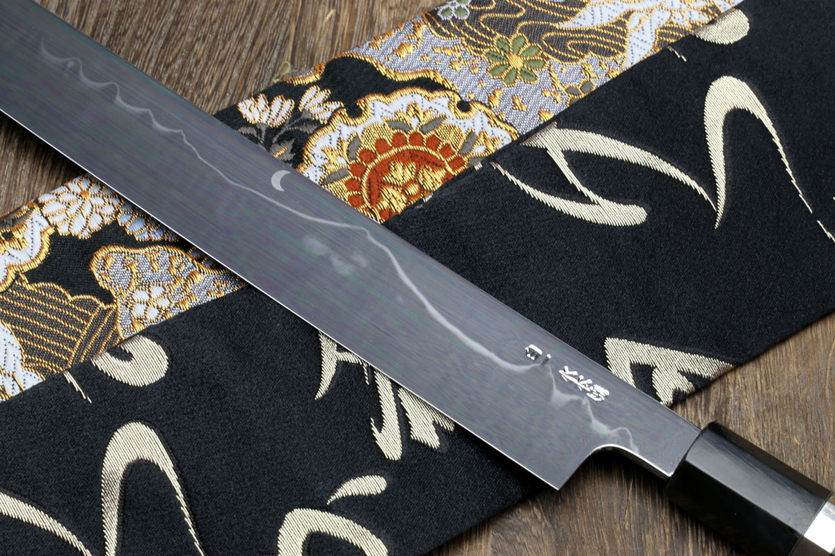 Mirror-finished Japanese kitchen knife with dark handle and silver-toned bolster