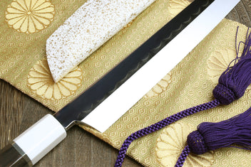 Japanese sushi sashimi knife showing black blade and white handle cap with purple tassel