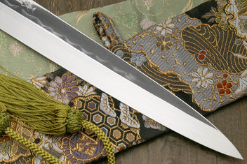 Japanese kitchen knife with mirror blade, ornate cloth sheath and green braided tassel