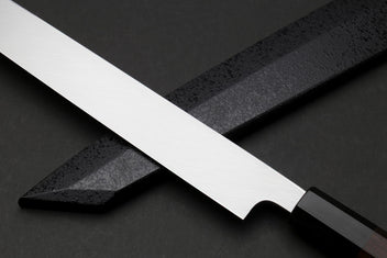 Japanese knife with silver mirrored blade and dark handle, angled view showing edge and curve.