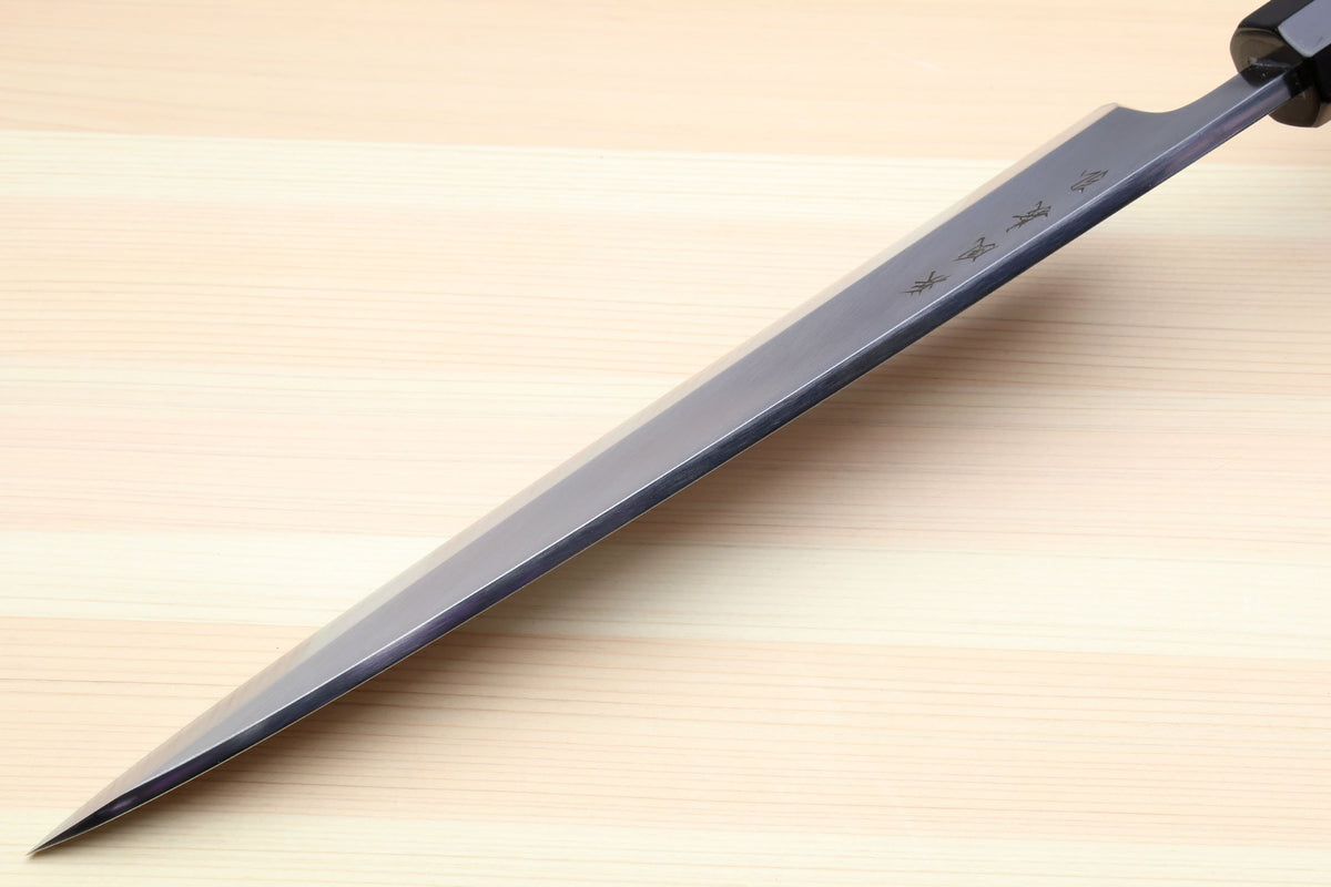 Japanese fish filet knife with dark handle and long silver blade, diagonal close-up