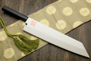 Japanese chef knife with dark ebony handle, white blade, and decorative green tassel