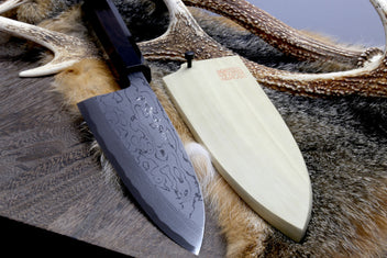Deba chef knife with patterned steel blade and light handle on fur hide with cord