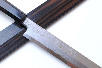 Japanese chef knife blade close-up with Damascus pattern and dark ebony handle