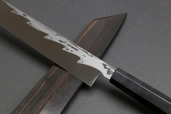 Japanese yanagi sushi knife with damascus blade and ebony handle, partial sheath visible