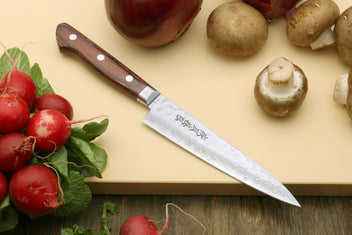 Damascus kitchen knife with dark wood handle and etched patterned blade