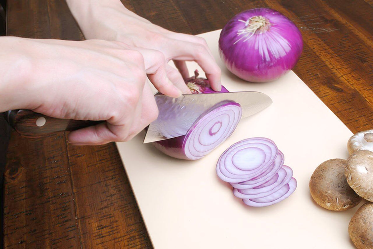 Paring knife slicing purple onion; Yoshihiro Damascus blade with dark wooden handle