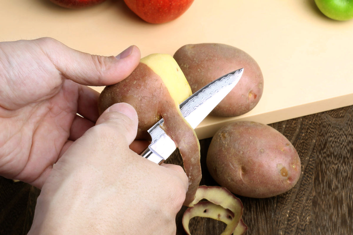 Paring knife with hammered Damascus blade, dark handle, cutting potatoes