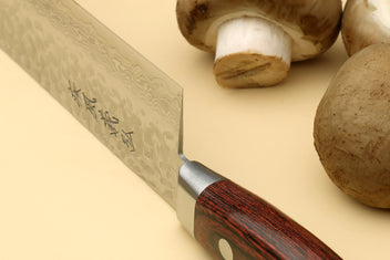 Nakiri vegetable knife angled view with hammered blade, dark wood handle, mushrooms nearby