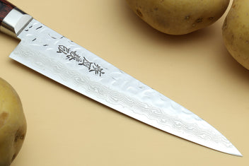 Petty knife blade close-up with etched damascus pattern and stamped characters